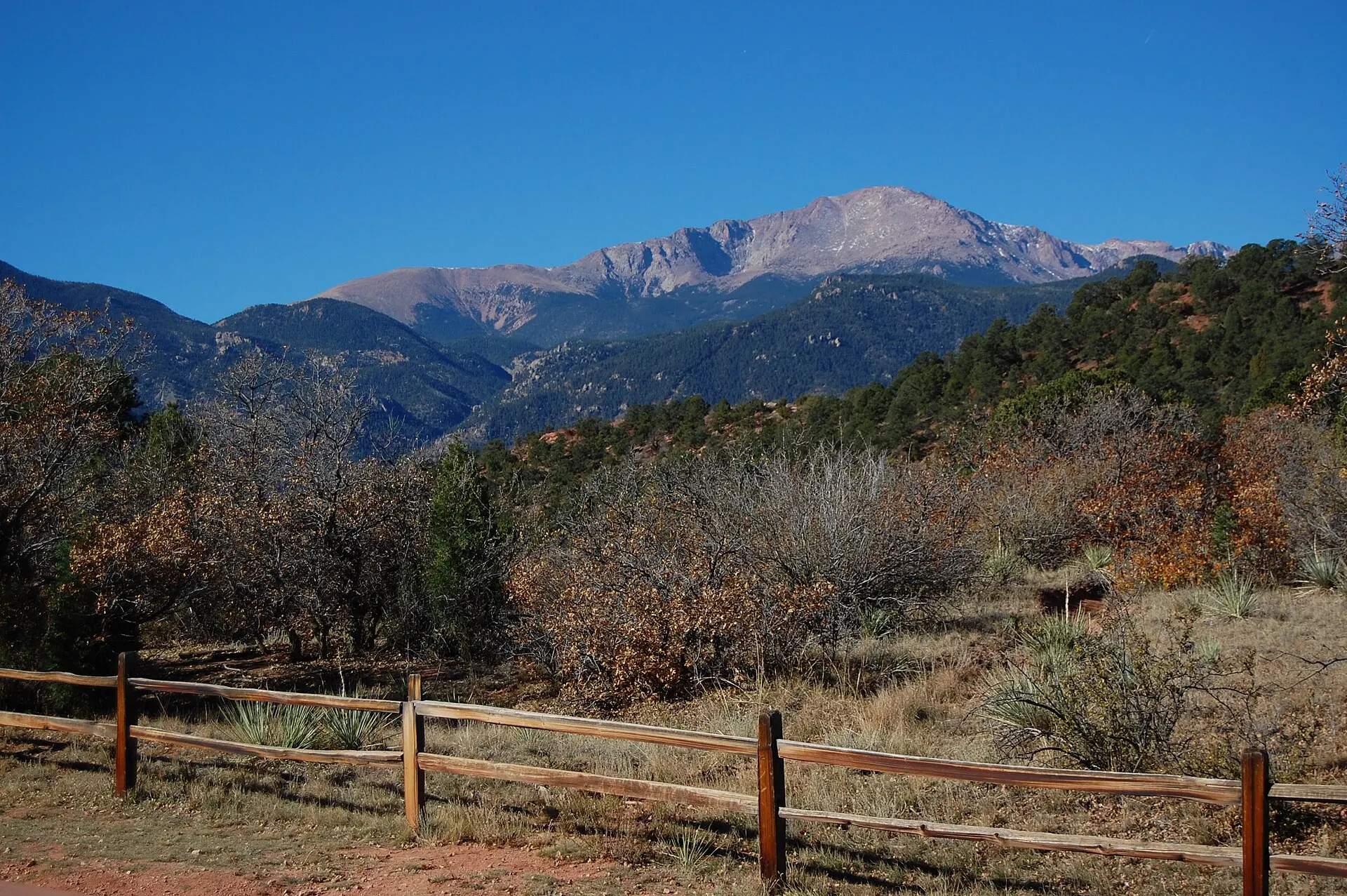 A split-rail fence and prairie grass in Garden of the Gods, with Pikes Peak in the distance